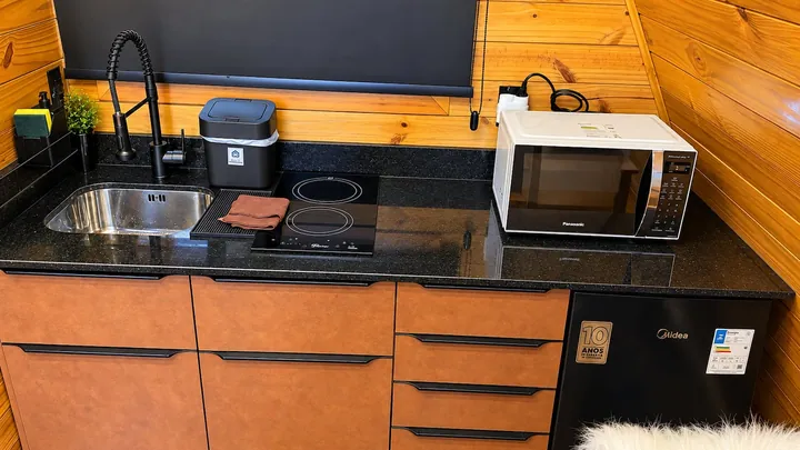 Cozinha com cooktop, micro-ondas e frigobar