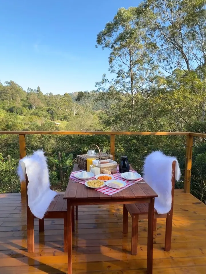 Mesa posta no deck, com a mata e os morros ao fundo
