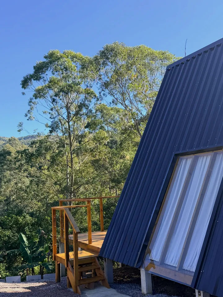 O telhado do chalé entre os eucaliptos, com a escada do deck